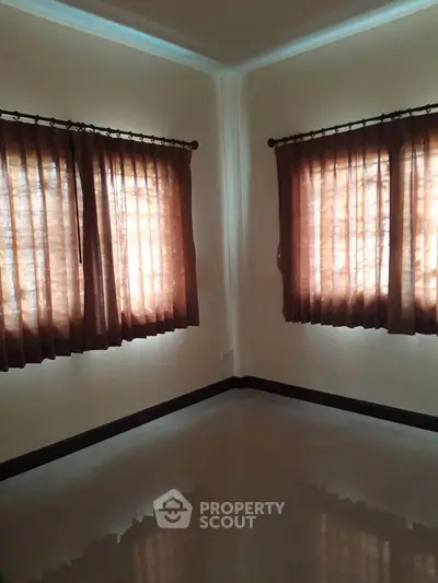 Spacious empty room with polished floors and elegant curtains, perfect for customization.