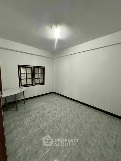 Spacious empty room with tiled flooring and natural light, perfect for customization.