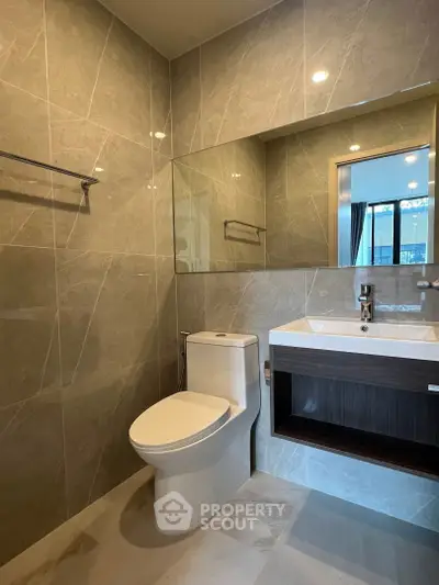 Modern bathroom with sleek design and large mirror in a contemporary apartment.