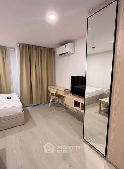 Modern bedroom with sleek furniture, large mirror, and natural light for a cozy living experience.