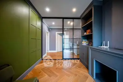 Modern living room with stylish green accent wall and herringbone wood flooring