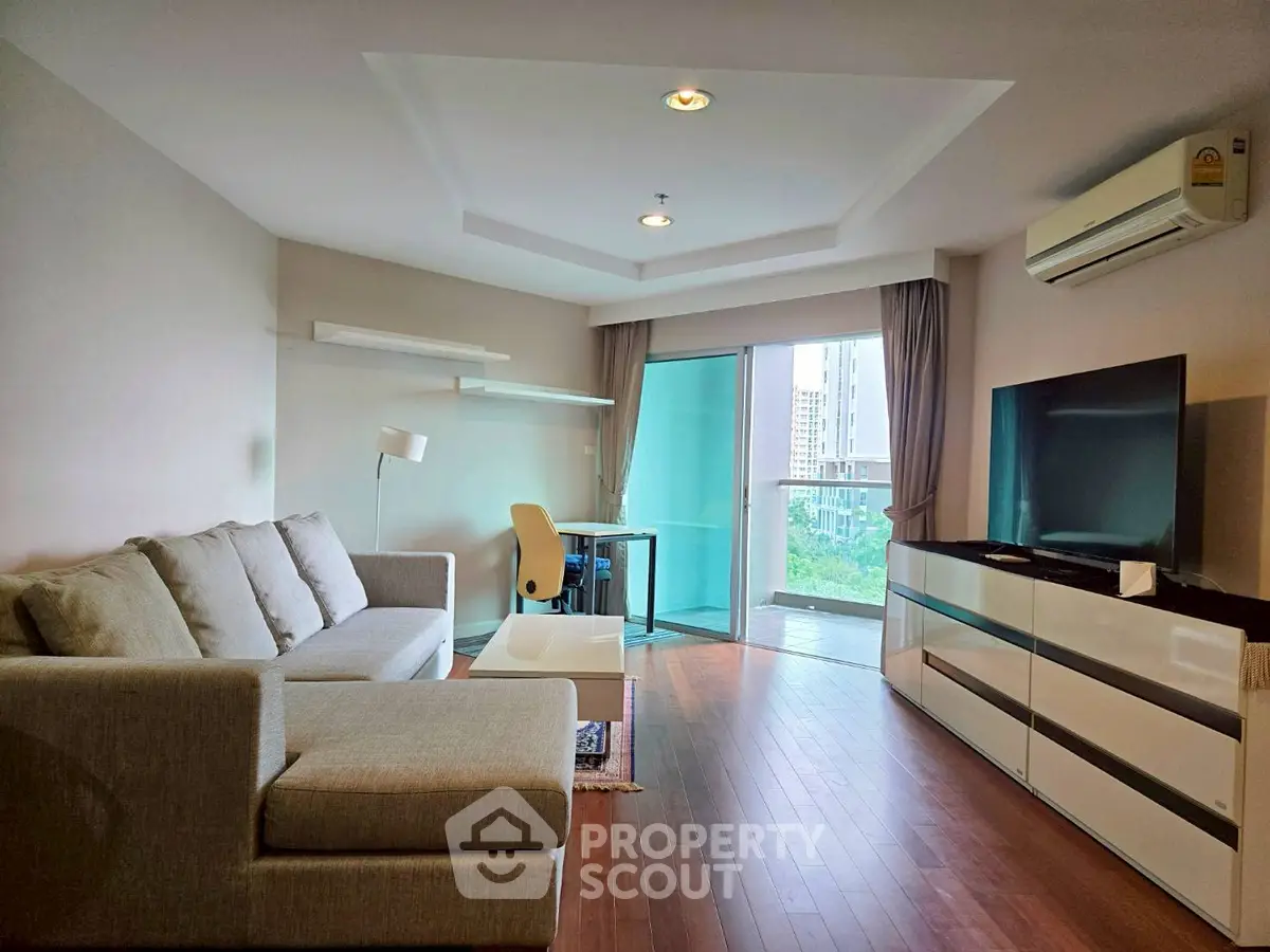 Modern living room with sleek furniture and city view from balcony.