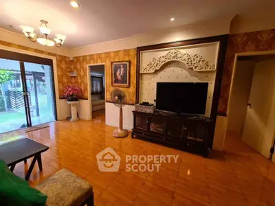 Spacious living room with elegant decor and large TV, featuring warm lighting and garden view.
