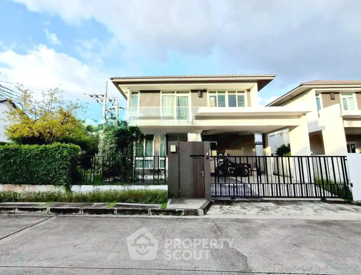 Modern two-story house with gated driveway and lush greenery