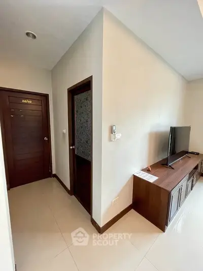 Modern apartment interior with sleek TV stand and wooden doors, showcasing a minimalist design.