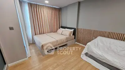 Modern bedroom with stylish decor and natural light, featuring a cozy bed and elegant wood flooring.