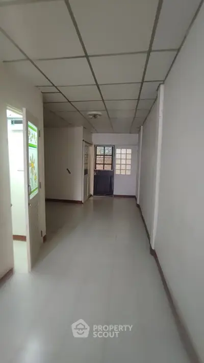 Spacious hallway with tiled flooring and decorative glass door, ideal for residential or office use.