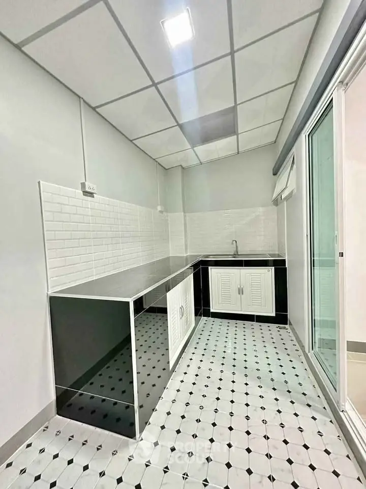 Modern kitchen with sleek black and white design, featuring a closed layout and stylish tile flooring.