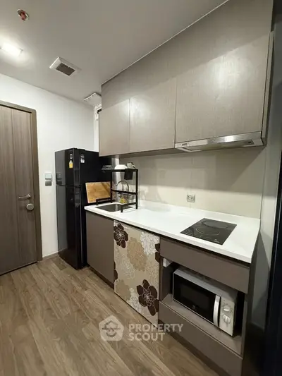 Modern kitchen with sleek cabinetry, electric stove, and microwave in a compact layout.