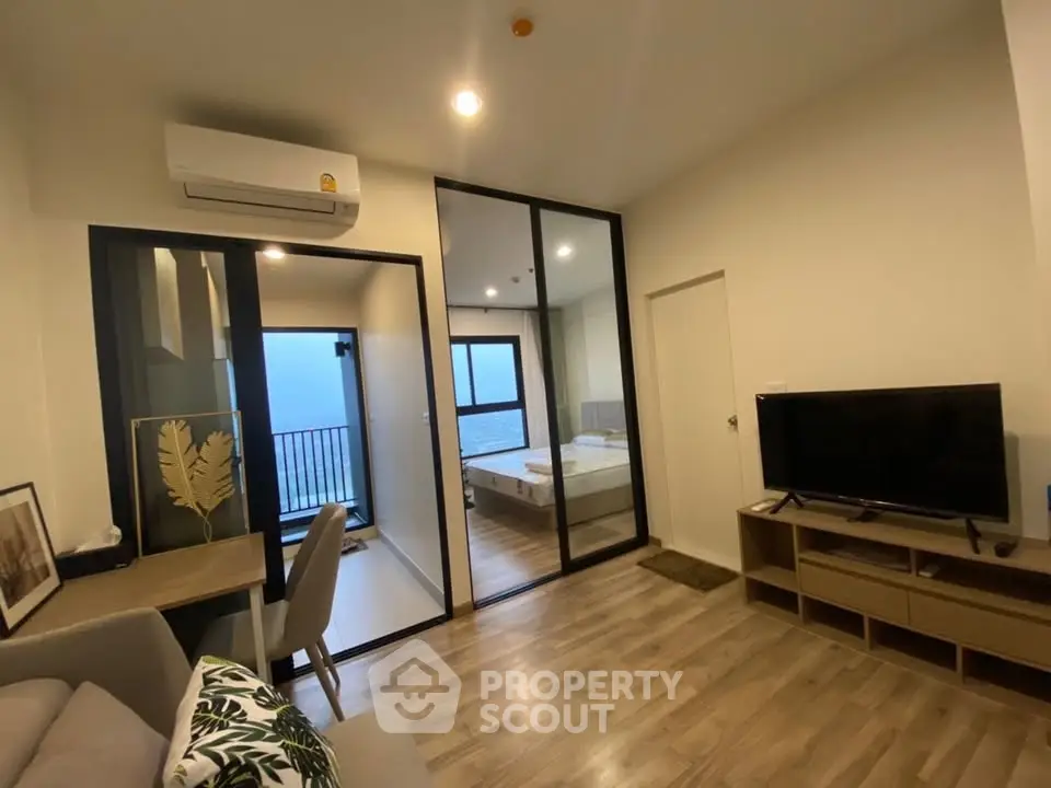 Modern apartment interior with open living room and bedroom, featuring wooden flooring and stylish decor.