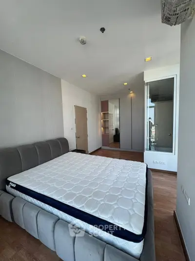 Spacious bedroom with modern design and ample natural light, featuring a large bed and sleek wardrobe.