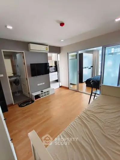 Modern studio apartment with open layout and wooden flooring, featuring a cozy bedroom and living area.