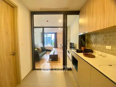 Modern open-plan apartment with sleek kitchen and cozy living area, featuring floor-to-ceiling windows and stylish decor.