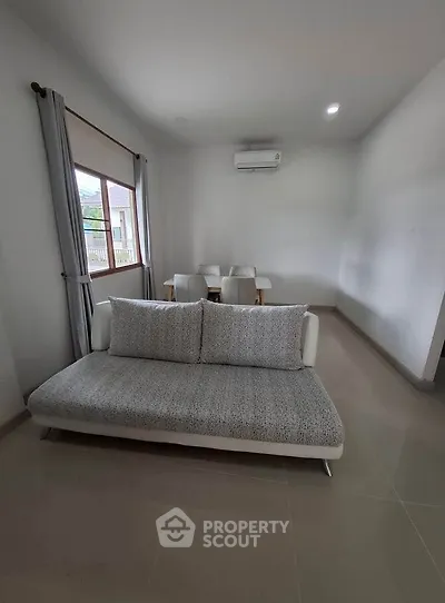 Modern living room with sleek sofa and dining area, featuring neutral tones and ample natural light.