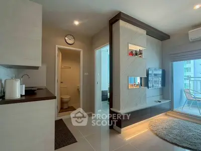 Modern apartment interior with open kitchen and cozy living area, featuring sleek design and balcony access.