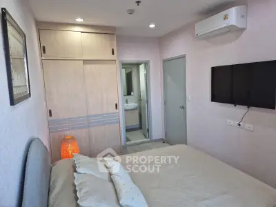 Cozy bedroom with modern decor, featuring a wall-mounted TV and built-in wardrobe, perfect for comfortable living.