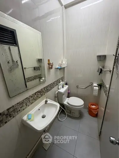 Compact bathroom with modern fixtures and tiled walls, featuring a sink and toilet.