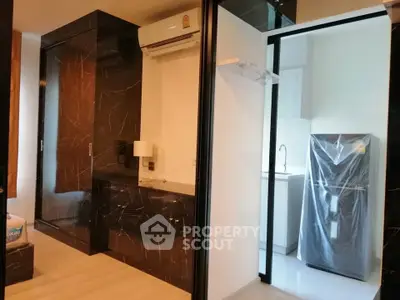Modern apartment interior with sleek black marble accents and a compact kitchen area.