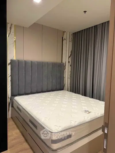Luxurious bedroom with plush headboard and elegant curtains in modern apartment.