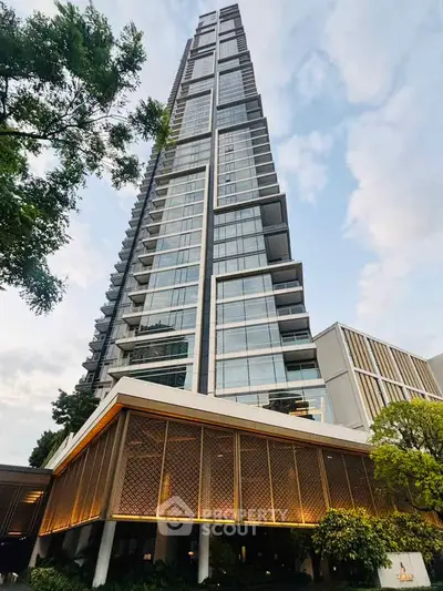 Stunning modern high-rise building with sleek glass facade and lush greenery at the base.