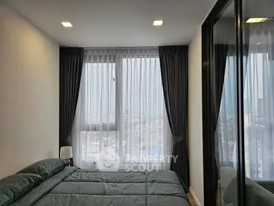Modern bedroom with large windows and city view, featuring sleek curtains and cozy bedding.