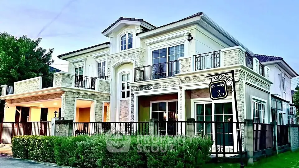 Luxurious two-story house with elegant balconies and lush greenery, perfect for upscale living.