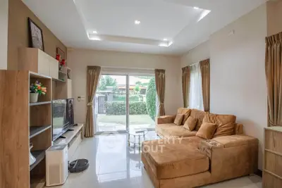 Spacious living room with modern decor and garden view, featuring a cozy sectional sofa and entertainment center.