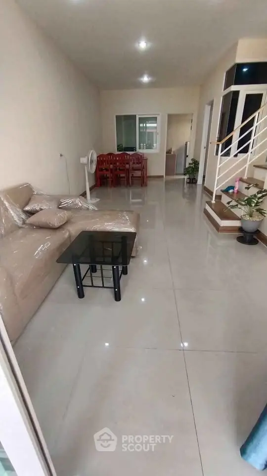 Spacious living room with modern furniture and elegant staircase in a stylish home.