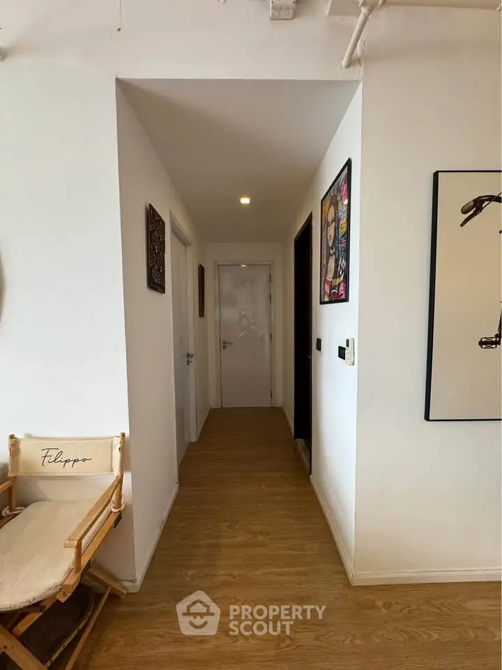 Stylish hallway with wooden flooring and modern art decor in a contemporary apartment.