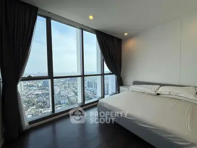 Luxurious bedroom with panoramic city view from floor-to-ceiling windows, featuring elegant decor and natural light.