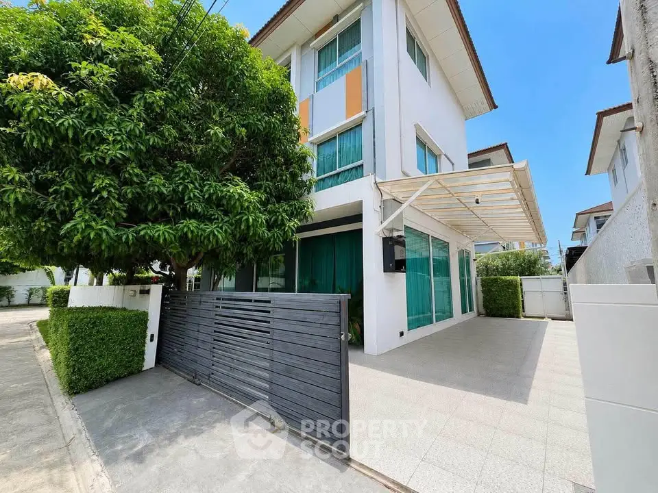 Modern three-story house with spacious driveway and lush greenery in a serene neighborhood.