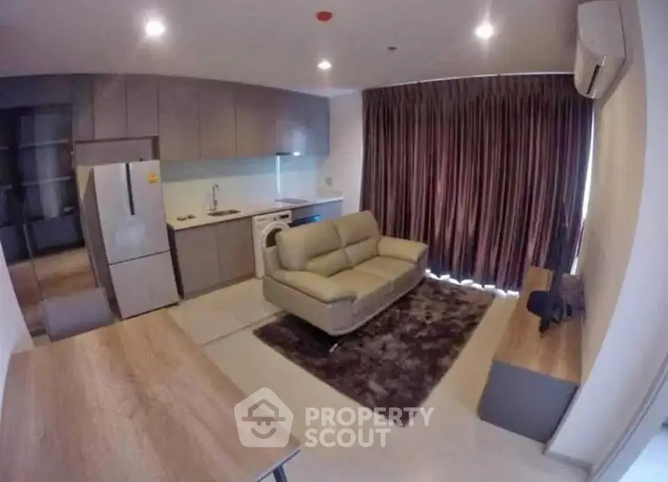 Modern living room with integrated kitchen, featuring sleek appliances and cozy seating area.