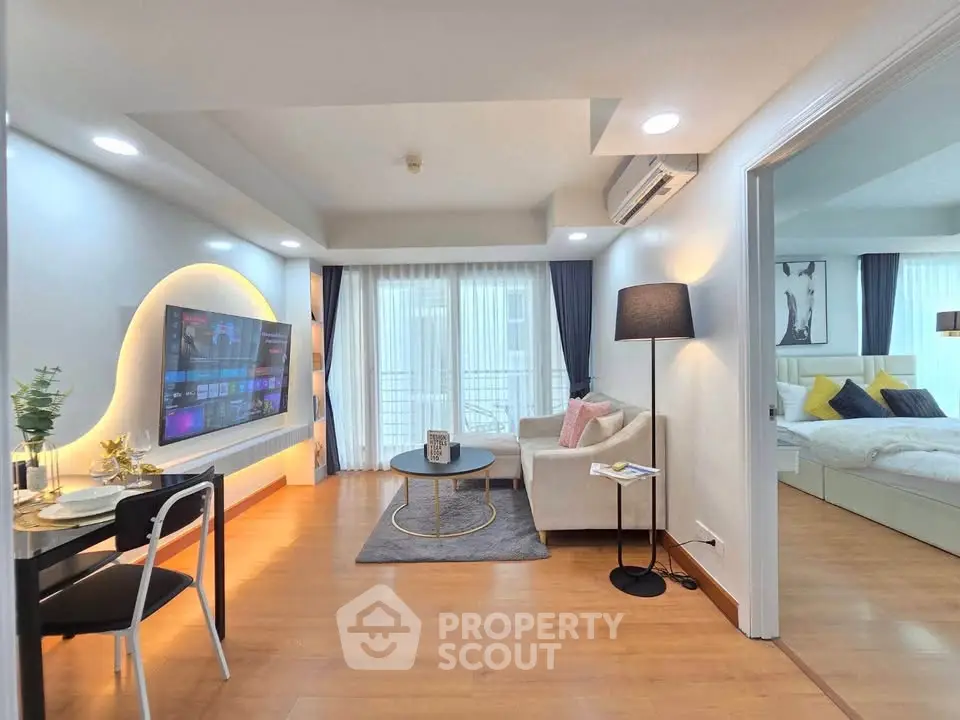 Modern living room with open layout and stylish decor, featuring a cozy seating area and large TV.