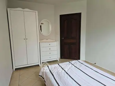 Cozy bedroom with white furniture and wooden door, perfect for relaxation.