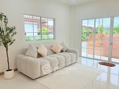 Bright and airy living room with plush sofa and large windows offering garden views.