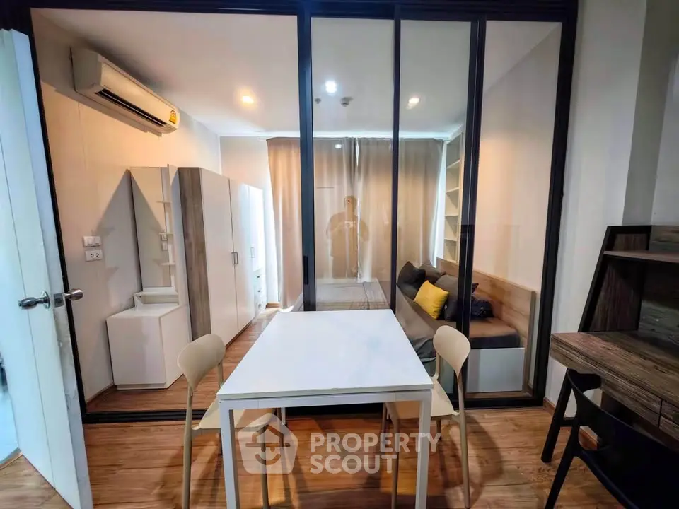 Modern apartment interior with glass partition, cozy living area, and stylish dining space.