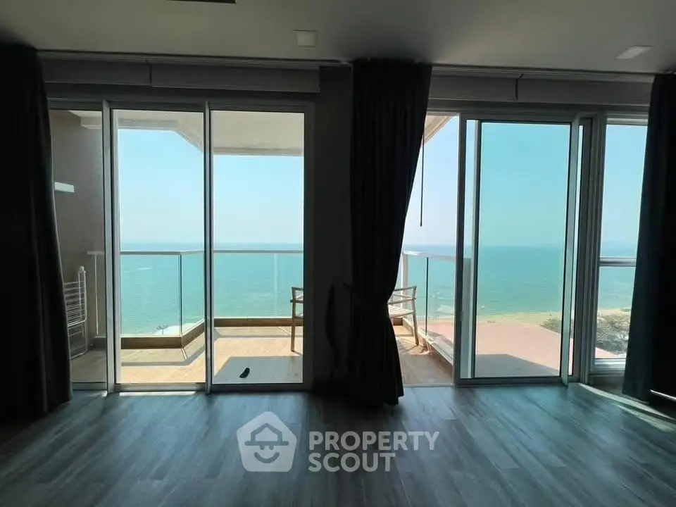 Stunning ocean view from modern apartment with large balcony and floor-to-ceiling windows.