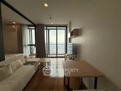 Modern living room with large windows and city view, featuring stylish furniture and wooden flooring.