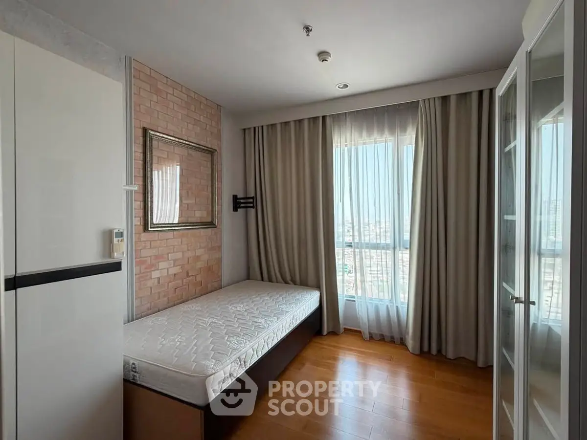 Modern bedroom with large window and wooden flooring in a stylish apartment.