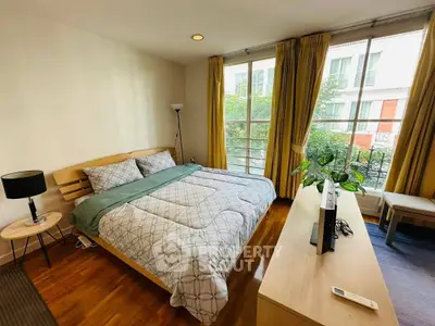 Bright and cozy bedroom with large windows and modern furnishings in a stylish apartment.