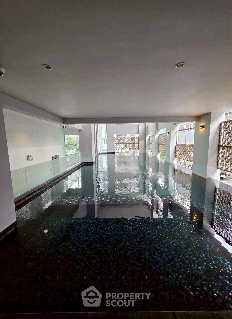 Luxurious indoor pool with modern design and ambient lighting in upscale residential building.