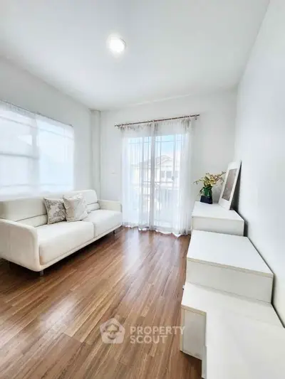 Bright minimalist living room with white sofa and wooden flooring