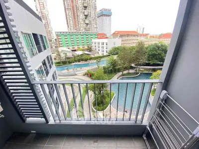 Stunning balcony view overlooking a luxurious pool and modern cityscape, perfect for urban living.
