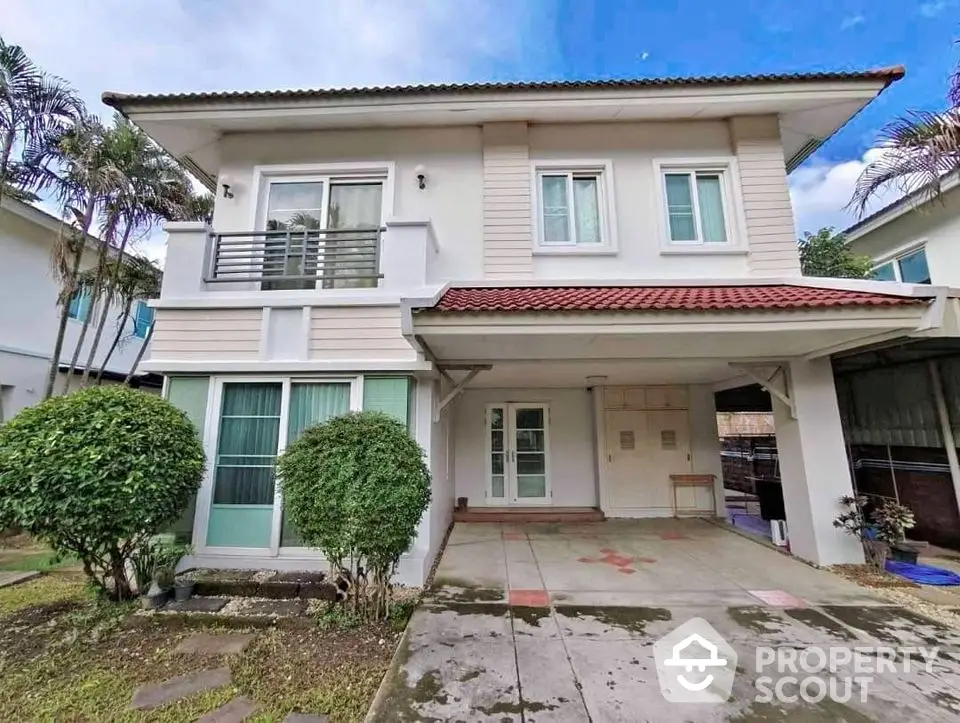 Charming two-story house with red-tiled roof and lush greenery in a serene neighborhood.