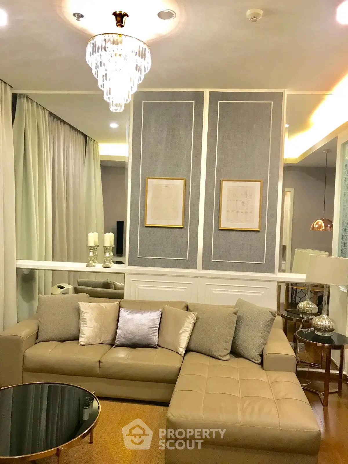 Luxurious living room with elegant chandelier and plush beige sofa in modern apartment.