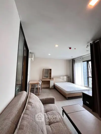 Modern studio apartment with cozy living area and large windows for natural light.