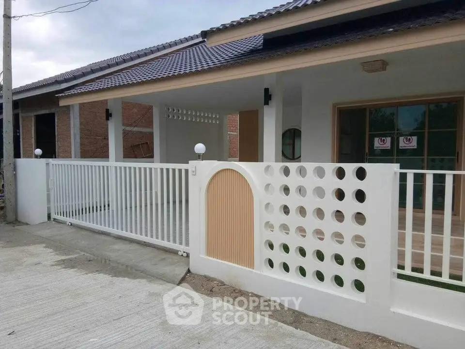Modern single-story house with unique circular fence design and spacious driveway.