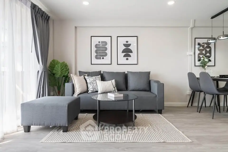 Modern living room with stylish decor, featuring a cozy gray sofa, chic artwork, and elegant lighting.