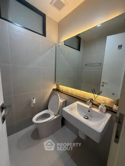 Modern bathroom with sleek design, featuring a wall-mounted sink and large mirror, perfect for contemporary living.
