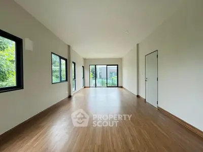 Spacious empty room with large windows and wooden flooring, ideal for customization.